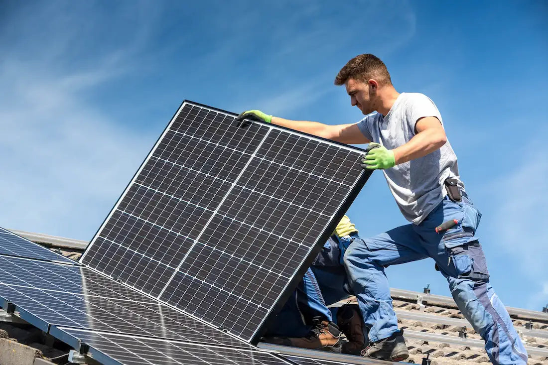 Handwerker installiert Solarmodul auf dem Hausdach bei sonnigem Wetter