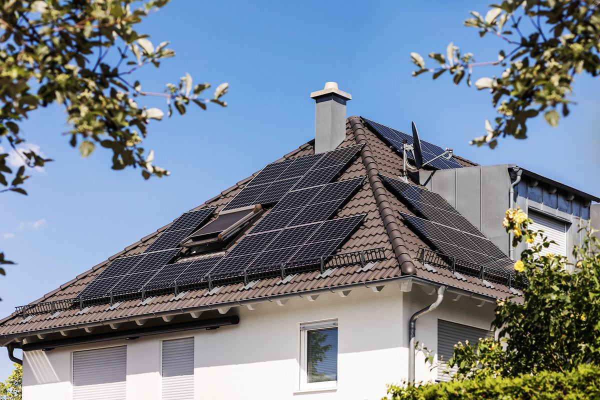 Walmdach mit Solarmodulen auf mehreren Dachflächen, Schornstein und Dachfenster